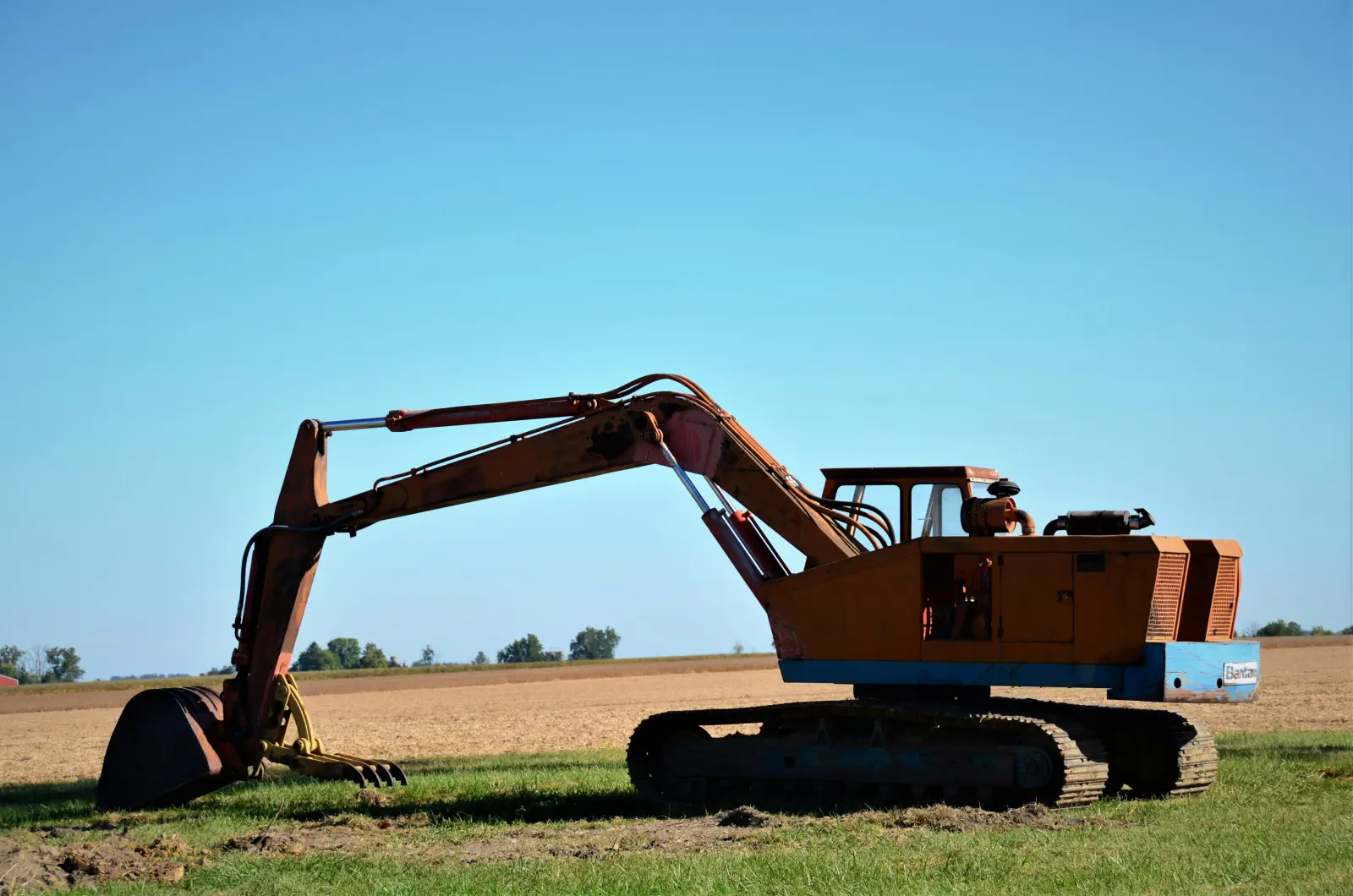 En gammal grävmaskin som står på en åker